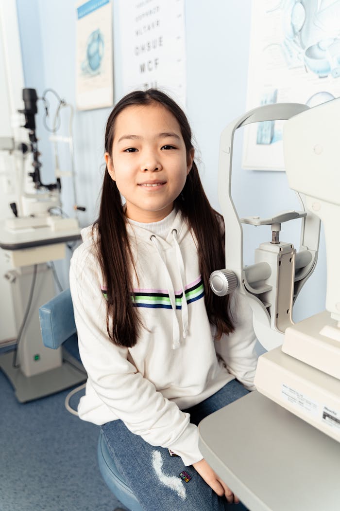 Asian girl smiling during an eye checkup at an optometry clinic, showcasing a relaxed and friendly atmosphere.